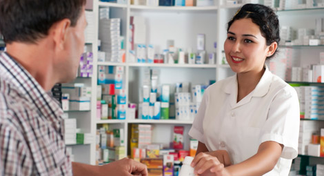 A pharmacist stood behind a counter with his arms crossed smiling